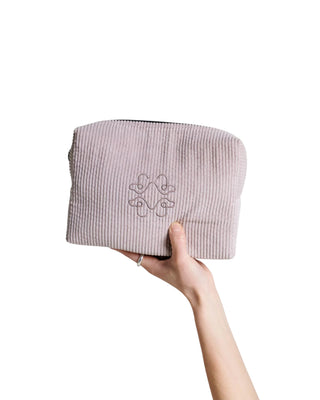 Beige necessär i manchester från Hundinspiration med broderad logotyp och svart dragkedja, hålls i en hand.