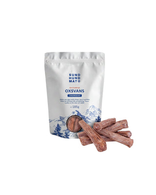 Hundinspiration frystorkad oxsvans från Sund hundmat i vit påse med tuggbitar av nötsvans framför.