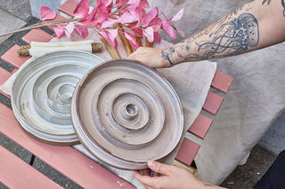 Hundinspiration handgjorda keramiska slow feed-matskålar i puderrosa och linnevit färg med spiralformad design.