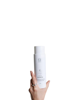 Hundinspiration Pennys Signature Shampoo i en vit flaska som hålls i en hand, professionellt hundschampo.