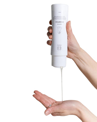 Hundinspiration Pennys Signature Shampoo som hälls från en vit flaska i en hand för skonsam hundtvätt