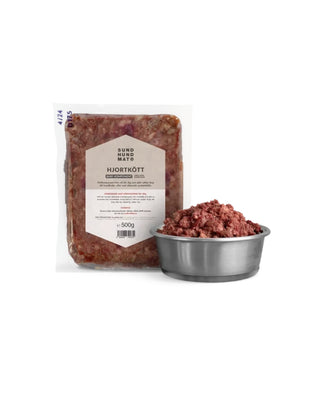 Hundinspiration Sund hundmat hjortkött i 500g förpackning bredvid en metallskål med rått kött för BARF-utfodring.